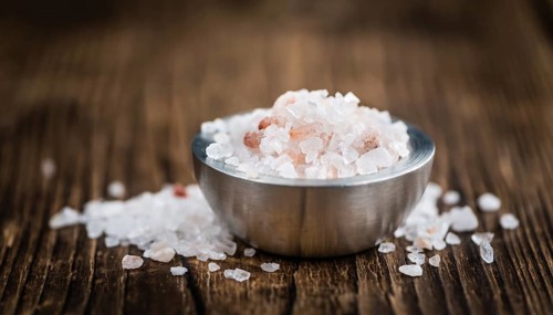 Salt (pink) on an old wooden table as detailed close-up shot (selective focus)