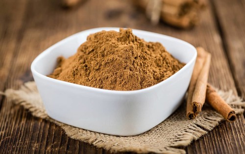 Cinnamon Powder as high detailed close-up shot on a vintage wooden table (selective focus)
