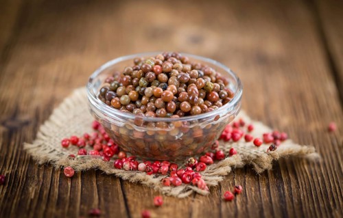 Preserved Pink Peppercorns on a vintage background as detailed close-up shot, selective focus