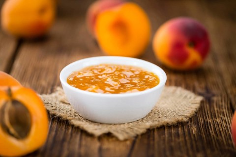 Apricot Jam on an old wooden table as detailed close-up shot (selective focus)