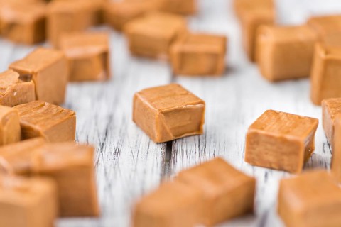Caramel pieces as high detailed close-up shot on a vintage wooden table (selective focus)