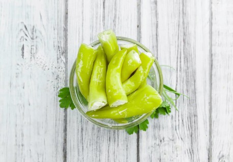Pimientos (filled with cream cheese) on rustic wooden background (close-up shot)