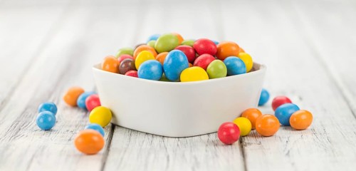 Cocolate coated Peanuts on rustic wooden background (close-up shot)