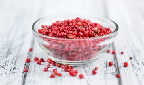 Pink Peppercorns as high detailed close-up shot on a vintage wooden table, selective focus