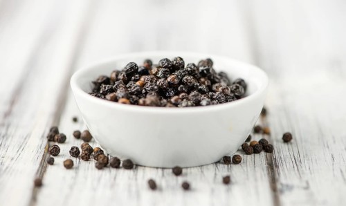 Preserved black Peppercorns on a wooden table as close-up shot