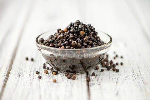 Wooden table with preserved black Peppercorns, selective focus, close-up shot
