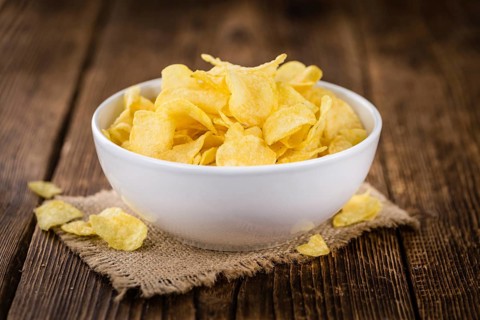 Cheese and Onion Potato Chips on a vintage background as detailed close-up shot (selective focus)