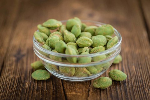 Peanuts (with Wasabi flavor) on an old wooden table as detailed close-up shot (selective focus)