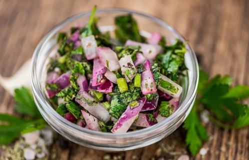 Healthy homemade Chimichurri on a wooden table as detailed close-up shot (selective focus)