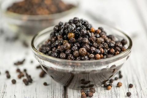 Black Peppercorns preserved on wooden background, selective focus, close-up shot