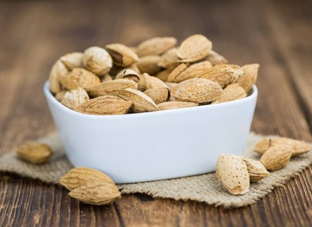 Roasted Almonds (in shell) on an old wooden table (close-up shot, selective focus)