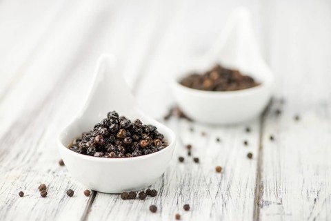 Preserved black Peppercorns on wooden background, selective focus, close-up shot