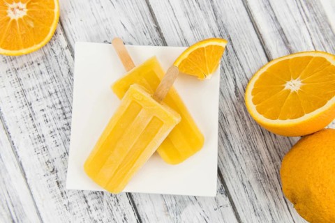 Orange Popsicles (selective focus, close-up shot) on a vintage background
