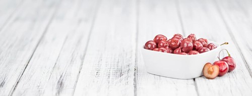 Preserved Cherries on an old wooden table as detailed close-up shot, selective focus