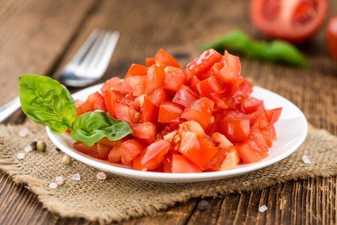 Tomatoes (diced) as high detailed close-up shot on a vintage wooden table (selective focus)