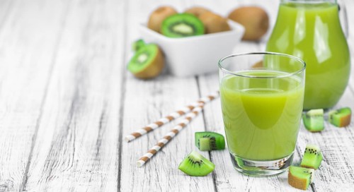 Wooden table with fresh made Kiwi Smoothie (close-up shot, selective focus)