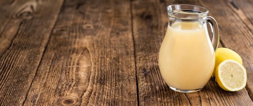 Fresh made Juice (lemon) on an old and rustic wooden table (selective focus, close-up shot)