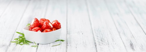 Filled Pimientos on an old wooden table as detailed close-up shot (selective focus)