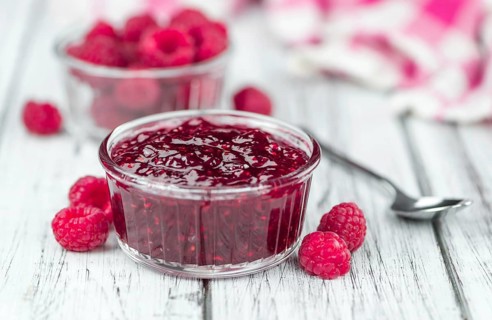 Homemade Raspberry Jam on an wooden table as detailed close-up shot, selective focus