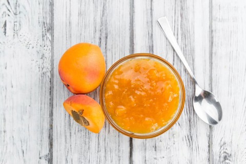 Apricot Jam as high detailed close-up shot on a vintage wooden table (selective focus)