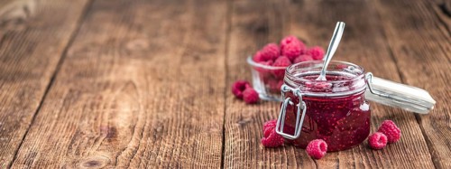 Fresh made Raspberry Jam on an old and rustic wooden table, selective focus, close-up shot