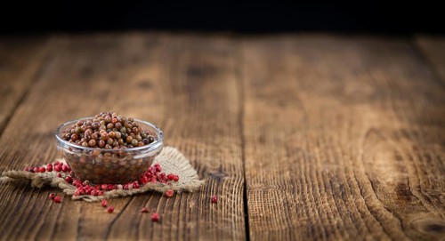 Fresh made Pink Peppercorns (preserved) on an old and rustic wooden table, selective focus,