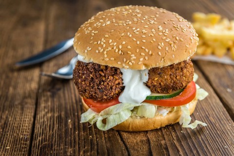 Vegetarian Falafel Burger on an old wooden table (close-up shot, selective focus)
