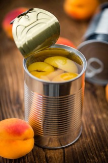 Canned Apricots on rustic wooden background (close-up shot)