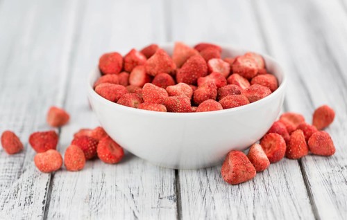 Strawberries (dried) as high detailed close-up shot on a vintage wooden table, selective focus