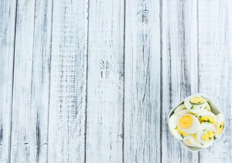 Halved Eggs on wooden background (close-up shot, selective focus)