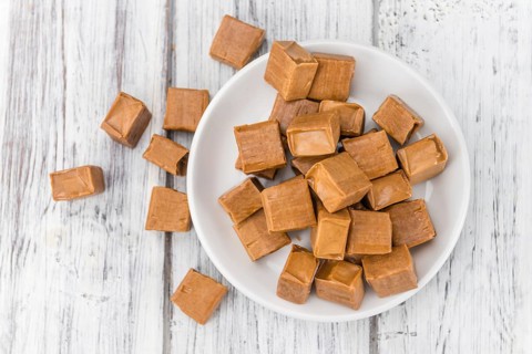 Portion of homemade Caramel on wooden background (selective focus, close-up shot)