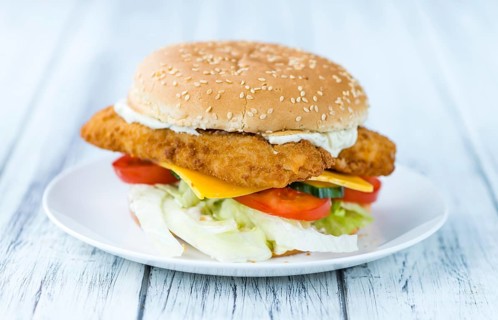 Fish Burger on wooden background (close-up shot, selective focus)