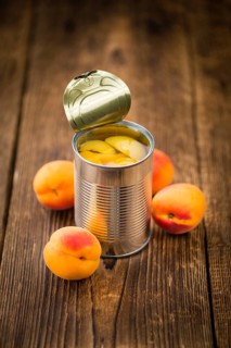 Canned Apricots on an old wooden table as detailed close-up shot (selective focus)