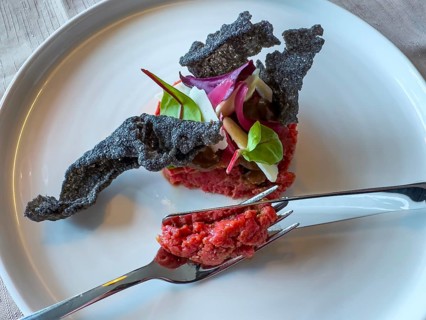 Fork and Knife on Plate with Bull Tartare with Black Charcoal Garlic and Tropea Onion with Parmesan