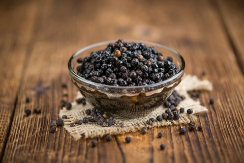 Preserved black Peppercorns on a wooden table as close-up shot