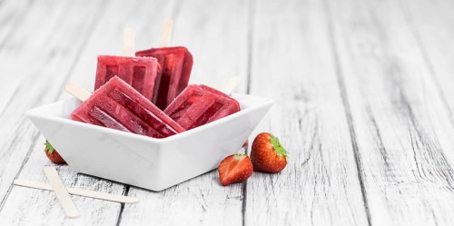 Old wooden table with homemade Strawberry Popsicles (close-up shot, selective focus)