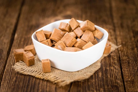 Portion of homemade Caramel on wooden background (selective focus, close-up shot)