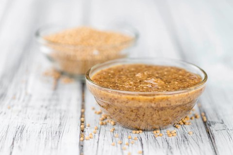 Mustard (sweet) on rustic wooden background (close-up shot)