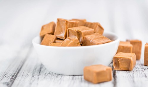 Portion of homemade Caramel on wooden background (selective focus, close-up shot)