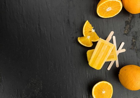 Some fresh made orange popsicles on a slate slab (selective focus, close-up shot)