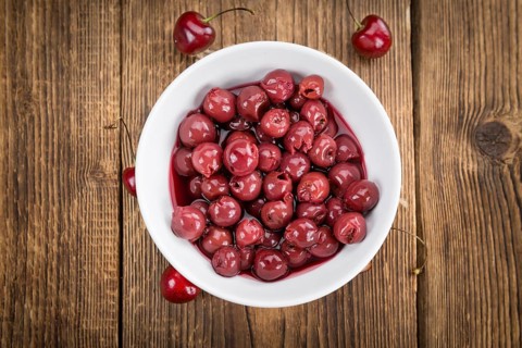 Canned Cherries as high detailed close-up shot on a vintage wooden table, selective focus