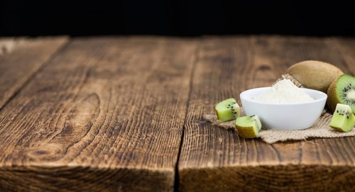 Bowl with fresh made Kiwi powder (close-up shot, selective focus) on an old wooden table