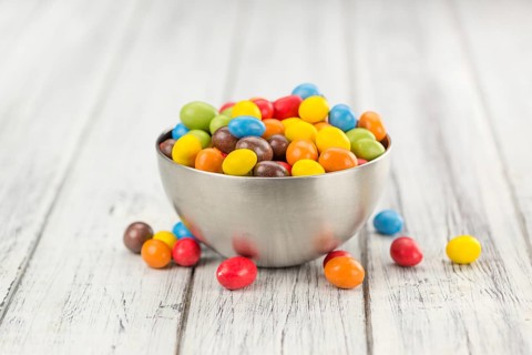 Cocolate coated Peanuts on rustic wooden background (close-up shot)