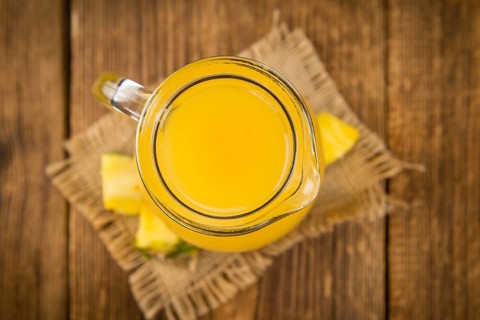 Pineapple Juice as high detailed close-up shot on a vintage wooden table, selective focus