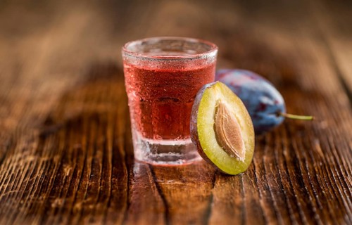 Plum Liqueur on rustic wooden background as close-up shot