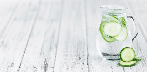 Fresh made Cucumber Water as high detailed close-up shot on a vintage wooden table, selective focus