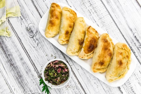 Wooden table with fresh homemade Empanadas (detailed close-up shot, selective focus)
