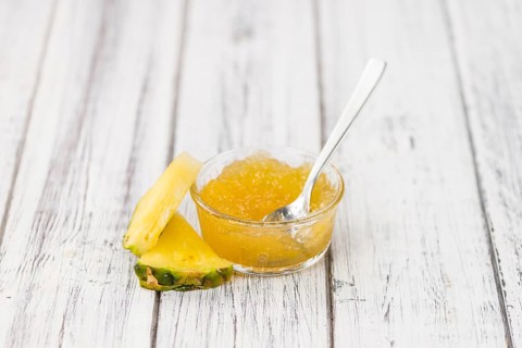 Pineapple Jam as high detailed close-up shot on a vintage wooden table, selective focus