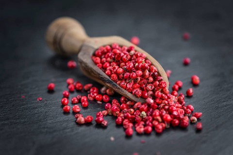 Portion of Pink Peppercorns on a rustic slate slab, selective focus, close-up shot