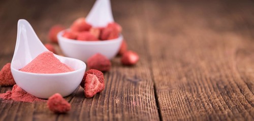 Strawberry powder as high detailed close-up shot on a vintage wooden table, selective focus
